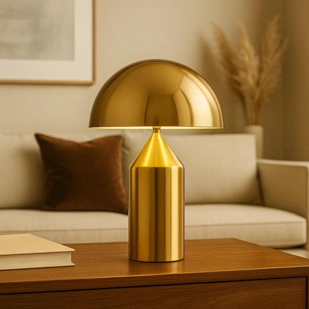 Lampe champignon dorée MORELLO posée sur une table en bois dans un salon au style contemporain, avec un canapé beige en arrière-plan, un coussin en velours brun et des pampas séchées, créant une ambiance chaleureuse et raffinée.